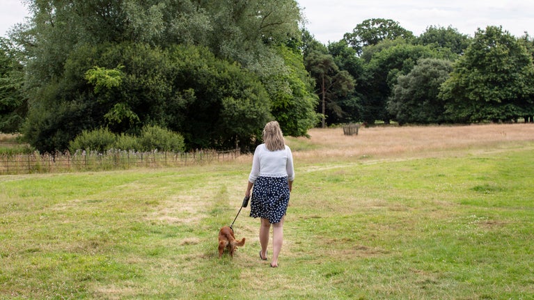 Woman walking a dog in an open field at Killerton